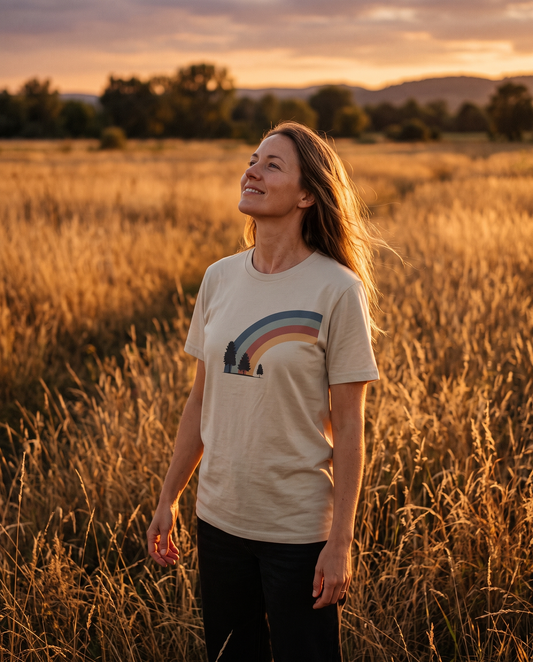 Woman standing in a golden late-summer field at evening light wearing a sand-colored tee, tall grass around her — why August feels different by Trees and Leaves